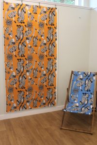 Image of a deck chair with blue fabric and matching yellow fabric hanging on the wall.
