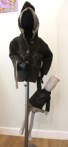 Image of a mannikin wearing a dark brown hoody and holding a toy.